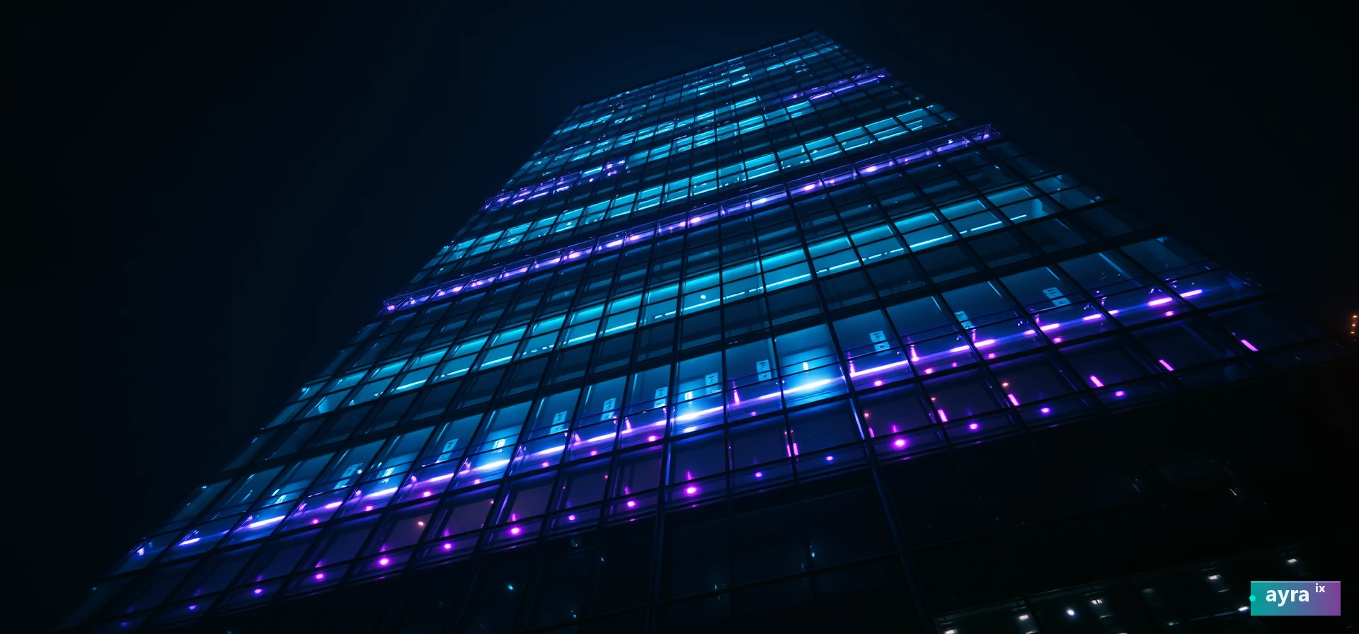 Monumental glass skyscraper facade lit with teal and violet light