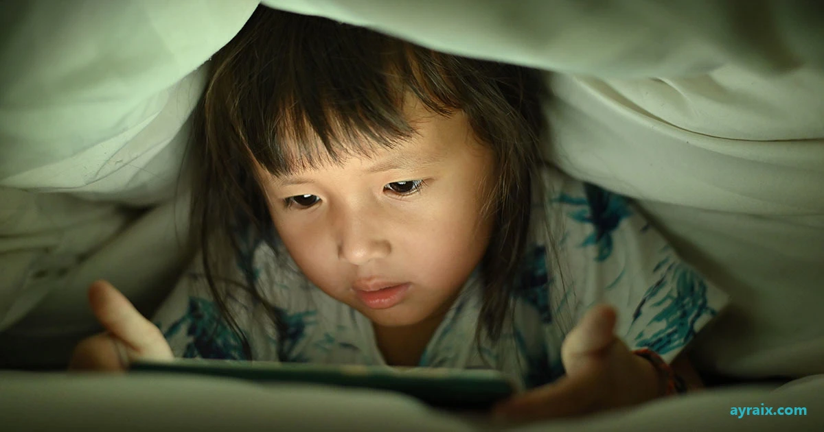 A child's face lit by a phone screen in a dark room, the glow doing the job a parent used to do