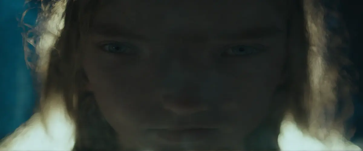 A teenage girl's face half-lit by a phone screen in a dark room, eyes reflecting blue light — the intimacy of AI companionship